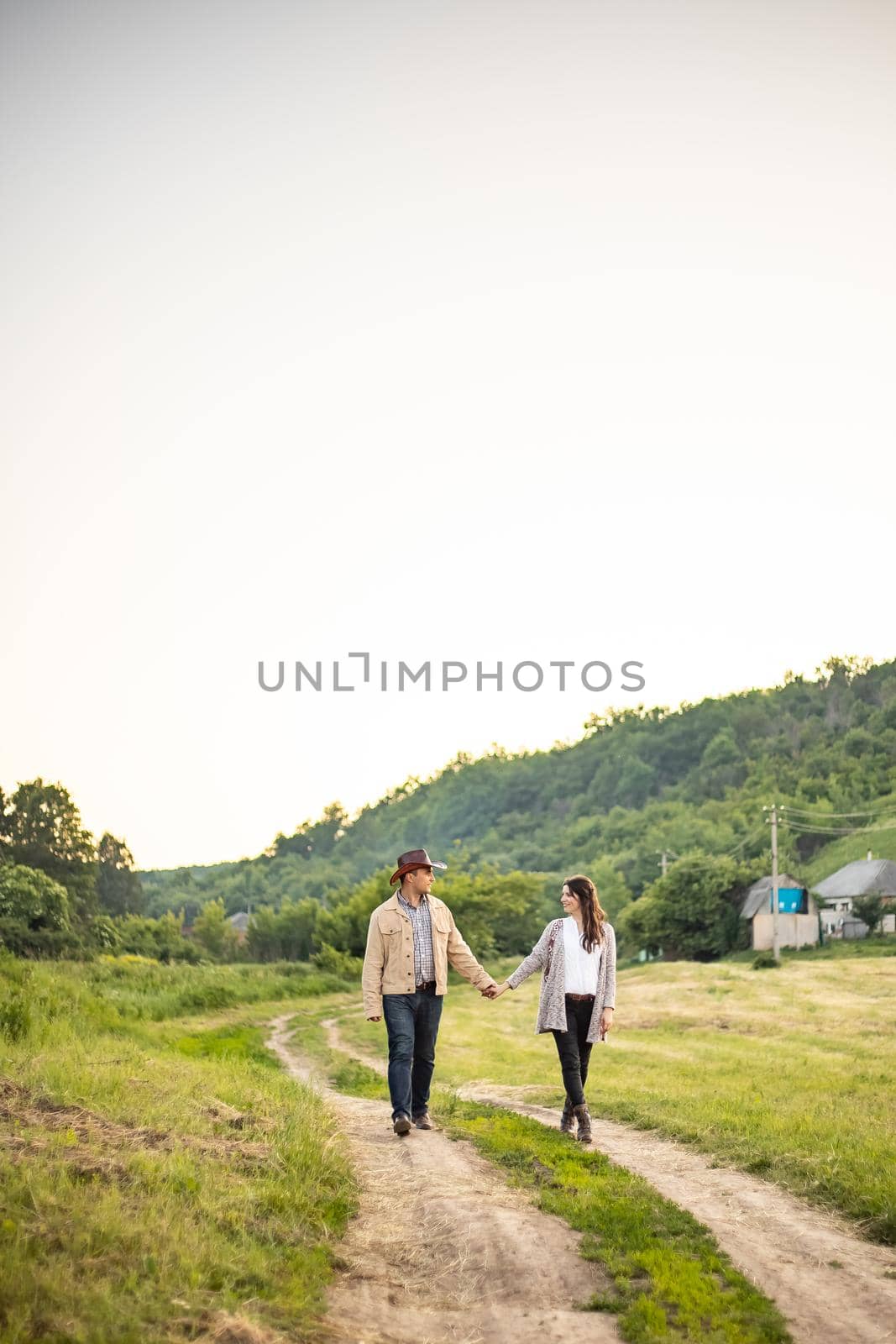 Caucasian heterosexual couple walks through an alley of cobblestones holding hands by the picturesque village of Fornalutx, Mallorca, Spain. Vertical photo.
