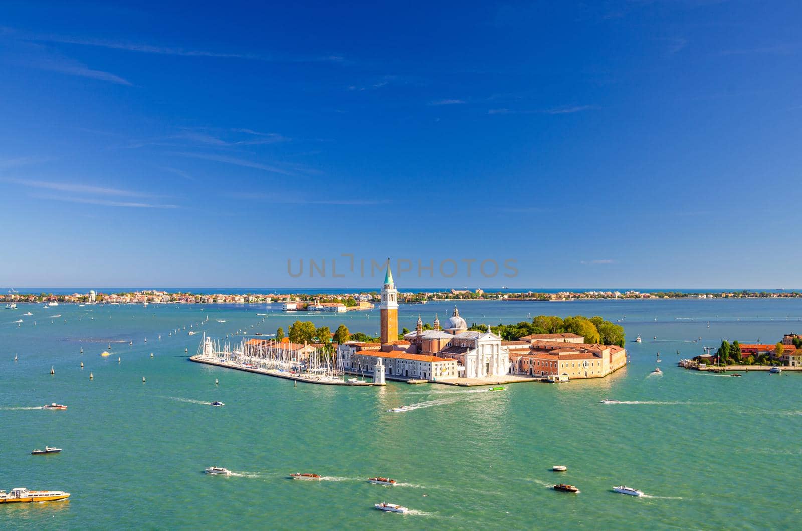 Aerial panoramic view of San Giorgio Maggiore island with Campanile San Giorgio in Venetian Lagoon, sailing boats in Giudecca Canal, Lido island, blue sky background, Venice city, Veneto Region, Italy