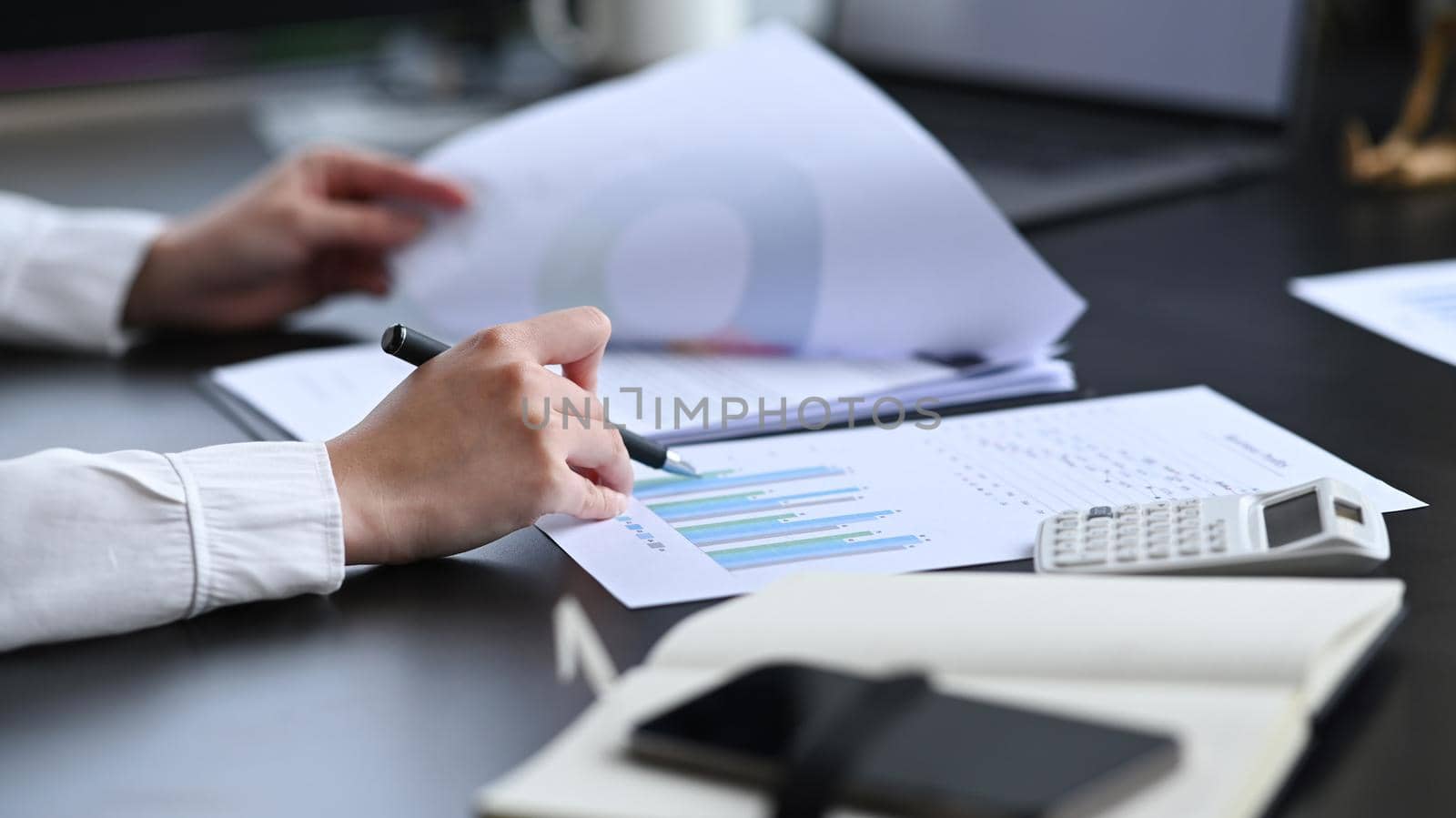 Cropped shot professional chartered accountant checking financial documents at her workplace.