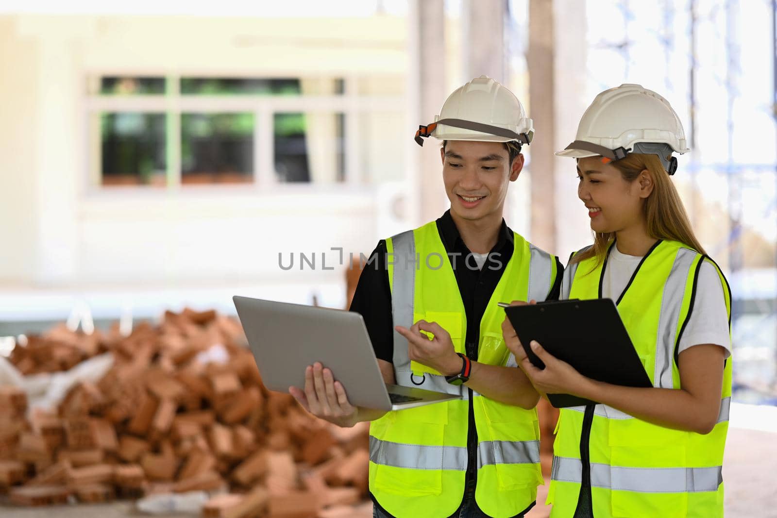 Civil engineer and architect discussing, planning development details together at construction site.