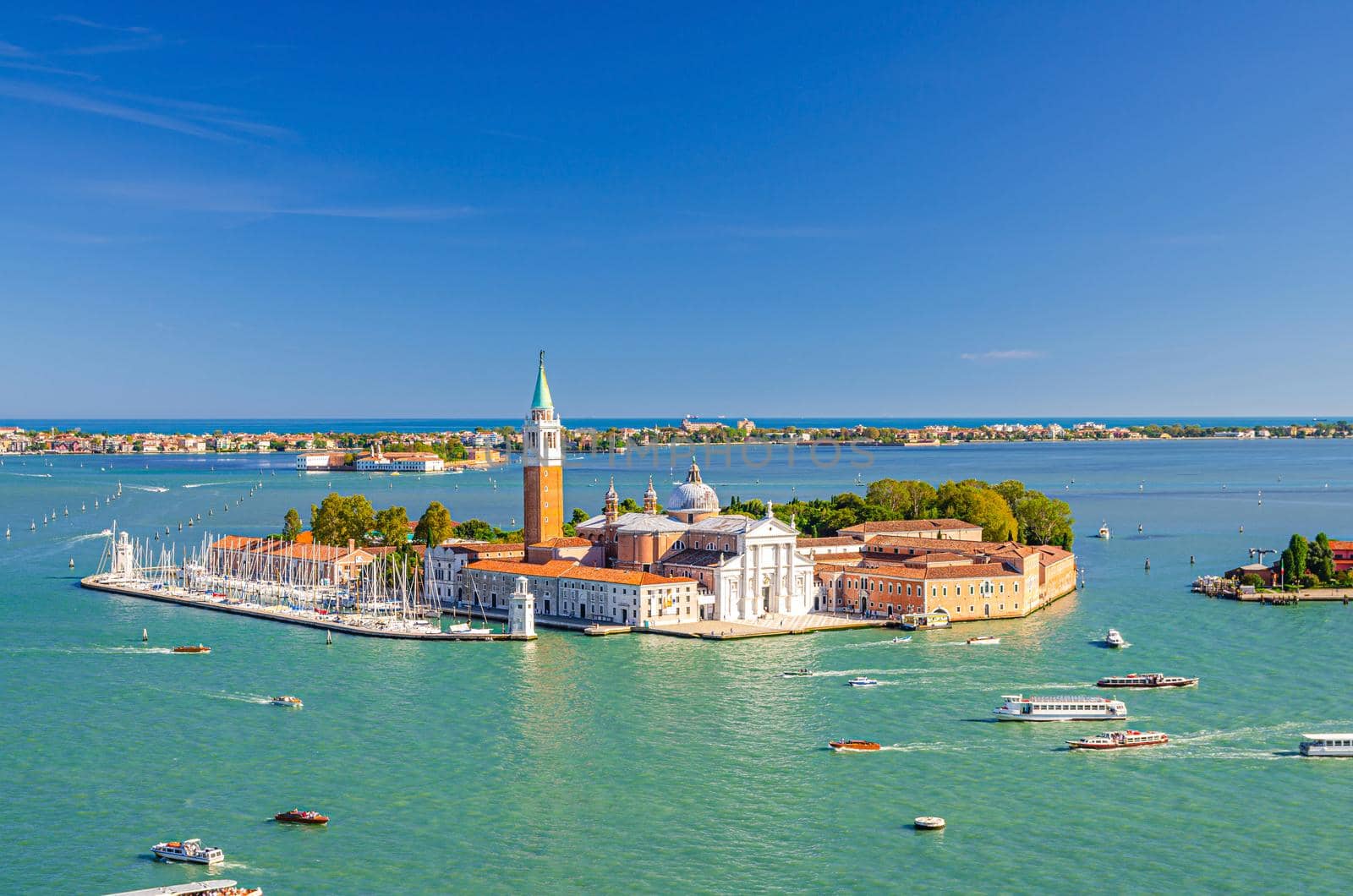 Aerial panoramic view of San Giorgio Maggiore island with Campanile San Giorgio in Venetian Lagoon, sailing boats in Giudecca Canal, Lido island, blue sky background, Venice city, Veneto Region, Italy