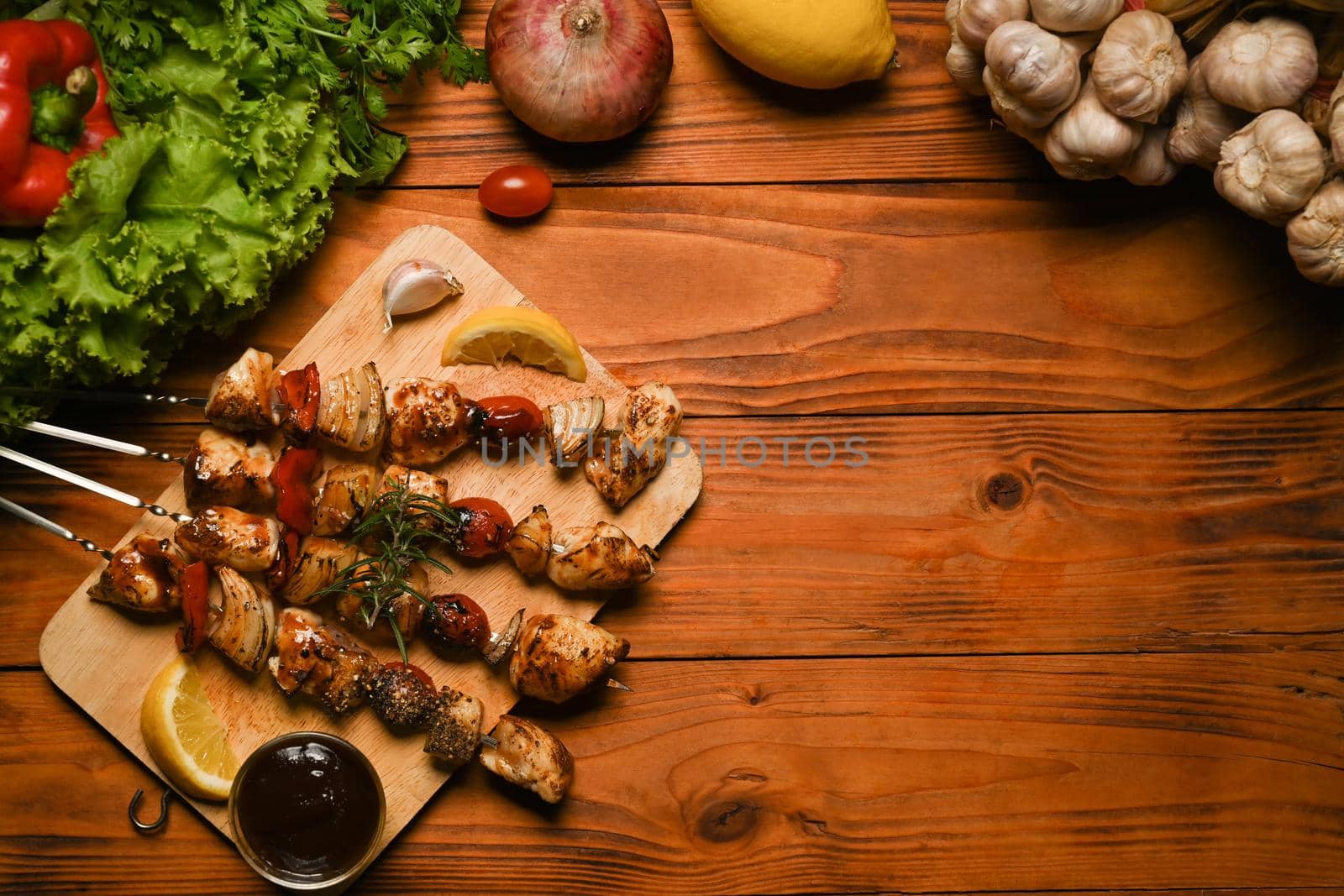 Grilled chicken meat skewers with cherry tomato, sweet pepper and onions on rustic wooden table. Barbecue, food, party concept.