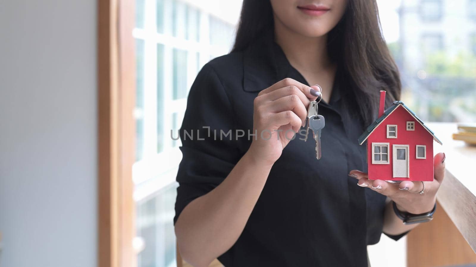 Young female financial advisor hand holding house model and keys. Insurance and real estate investment concept.