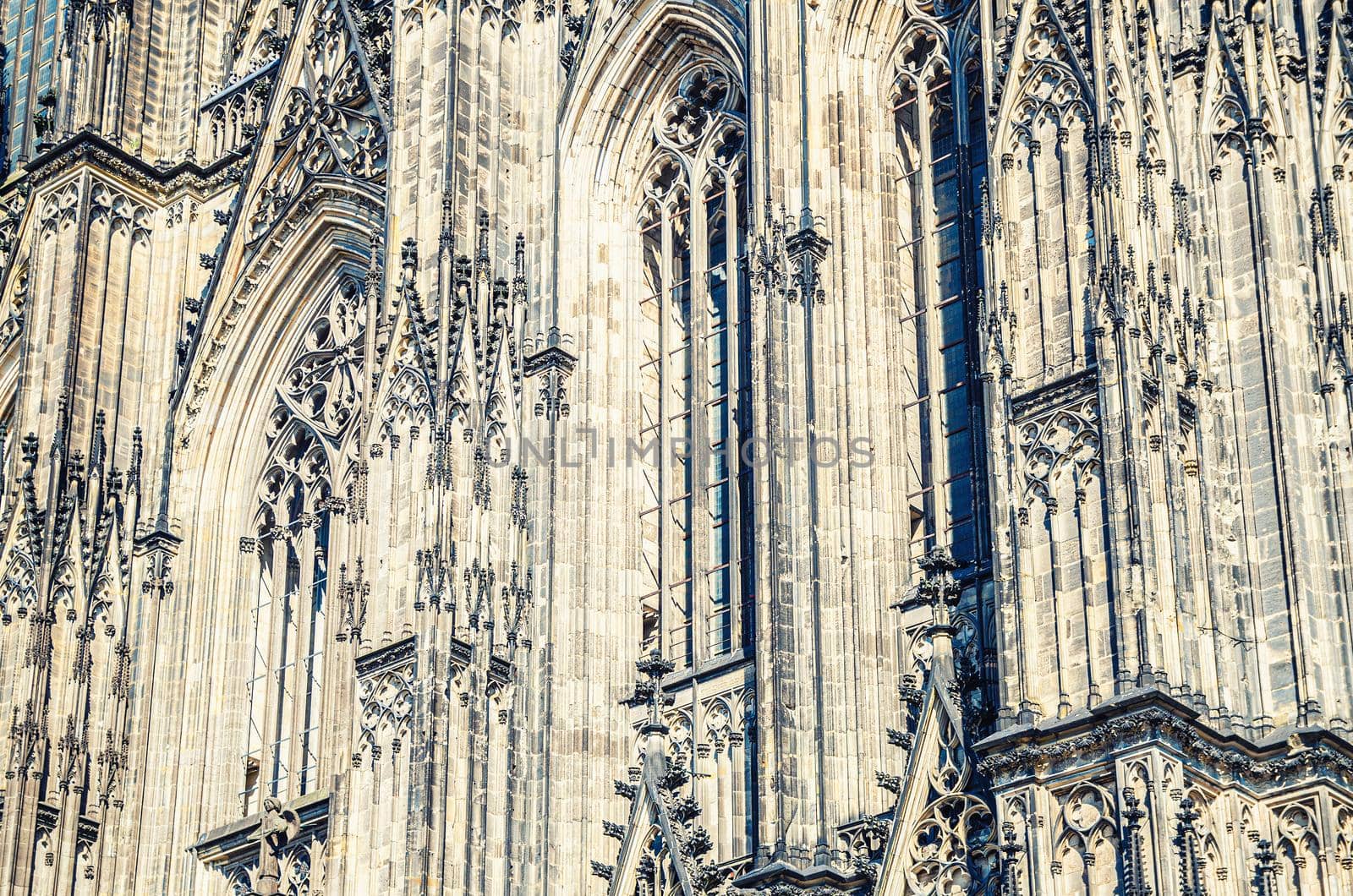 Close-up view of Cologne Cathedral Catholic Church gothic style building wall facade with ornaments, moldings stucco work and stained glass windows, North Rhine-Westphalia, Germany