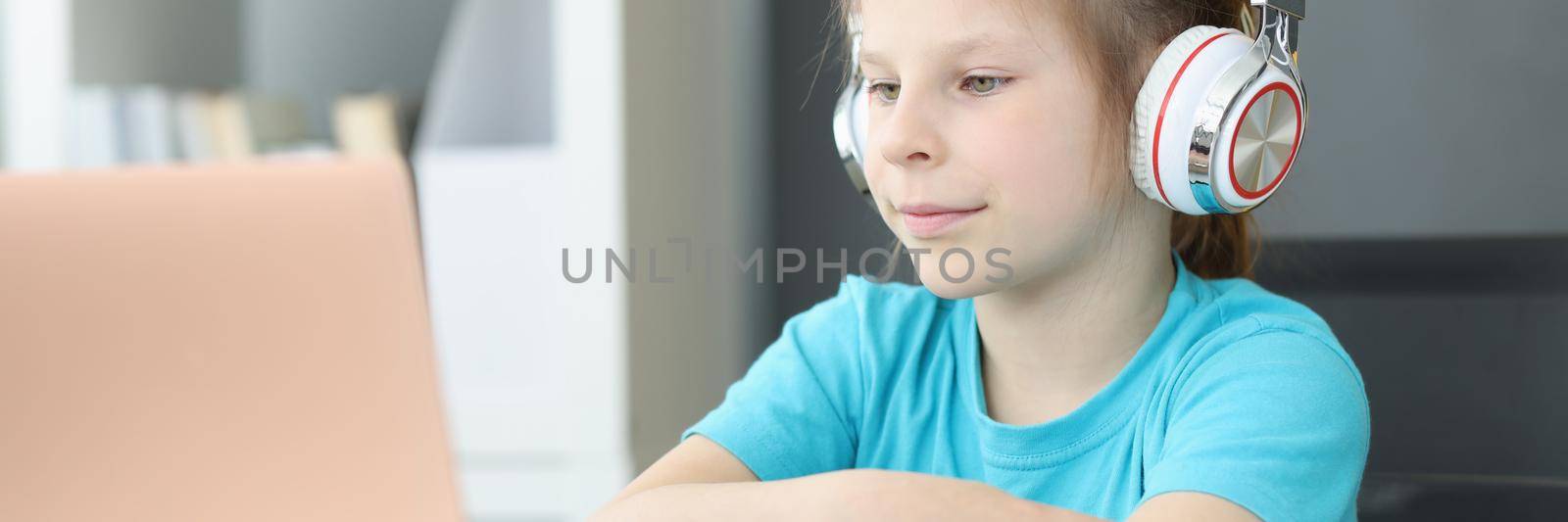 A student girl in headphones sits in front of a laptop by kuprevich