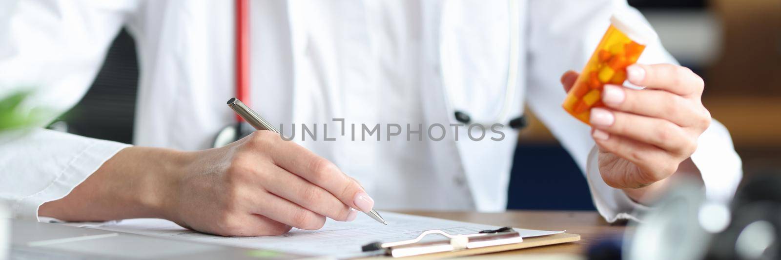A woman doctor is holding a medicine makes notes in the documents by kuprevich