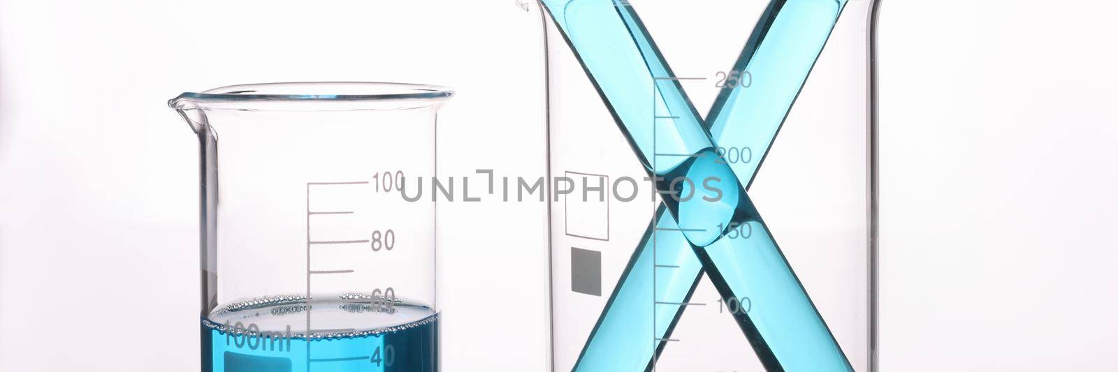 Blue liquid in measuring transparent vessels on a white background, close-up. Chemical experiments, pharmacology, microbiology experiment
