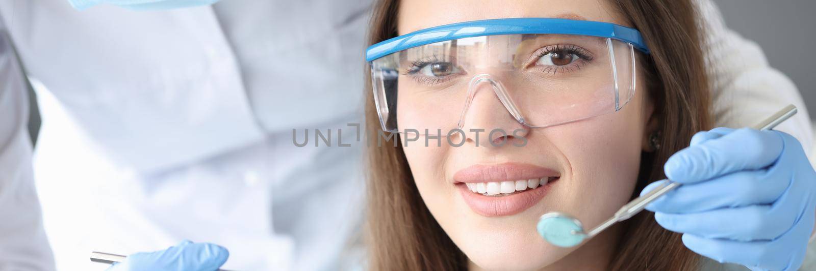 Beautiful young woman at the dentist appointment, close-up face. Diagnosis by an orthodontist, straight teeth, beautiful smile