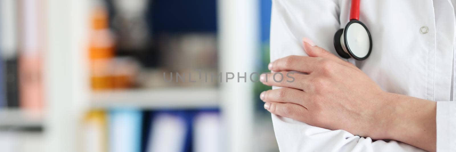 Woman doctor in uniform folded her arms over her chest close-up, blurry. Preparedness of medical personnel for a pandemic