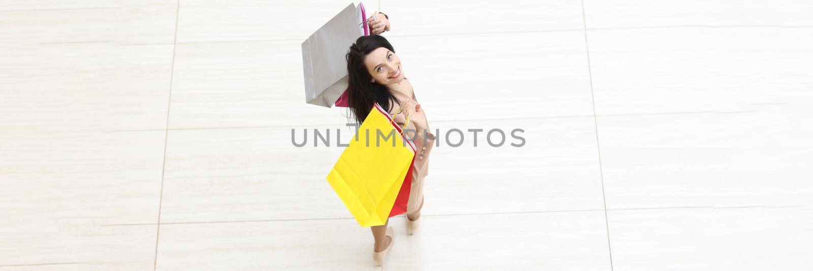 Happy beautiful woman with packages on the floor of a shopping mall, top view. Style and fashion, seasonal sale