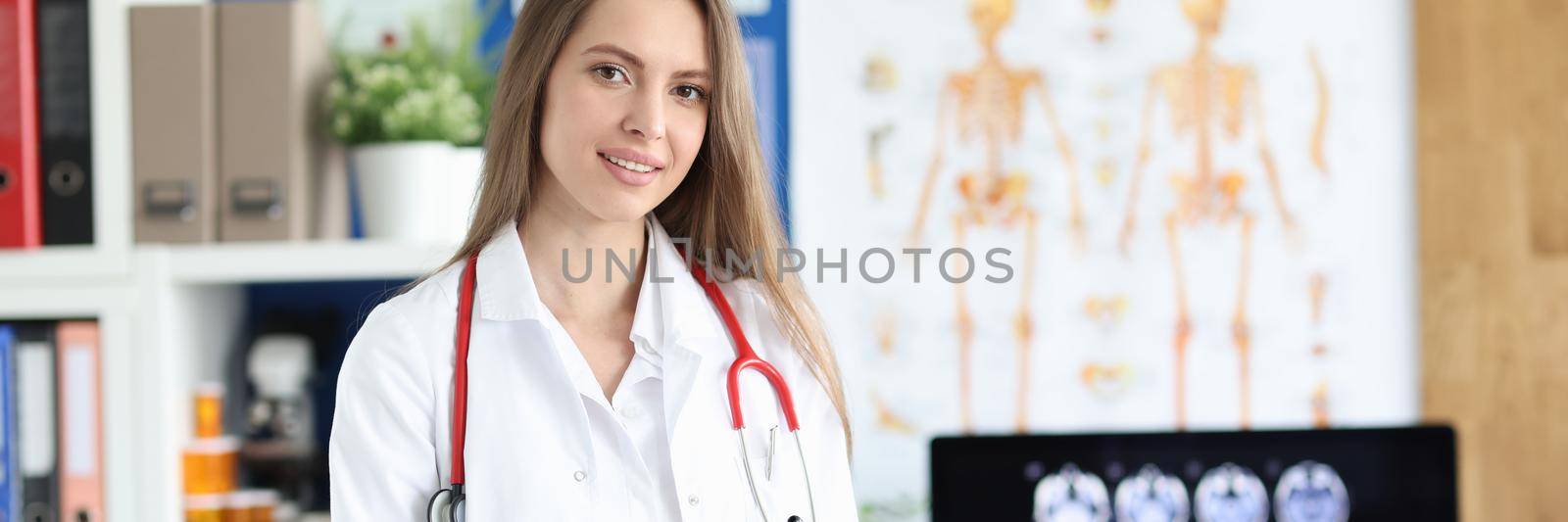A young female doctor in the clinic makes notes in the documents, close-up. Happy handsome medical professional, consultation