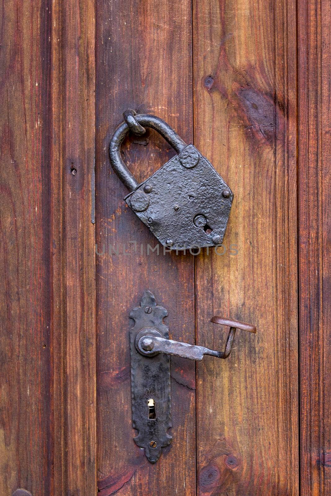 Door handle and a metal vintage padlock on the wooden door. True retro style. Close