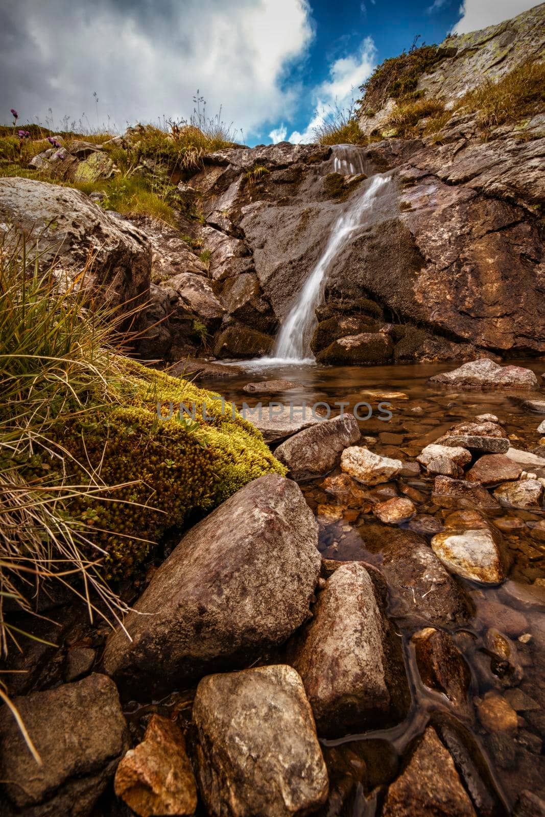 a beautiful mountain landscape with a brook and a small waterfall