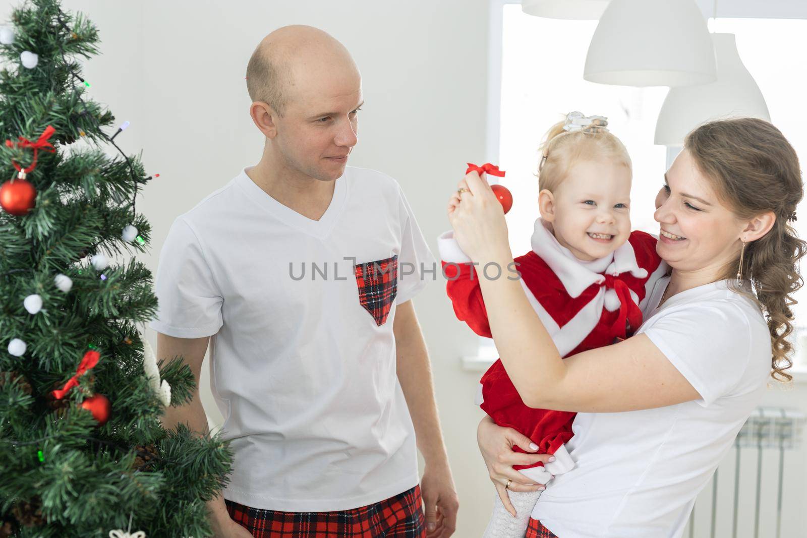 Baby child with hearing aid and cochlear implant having fun with parents in christmas room. Deaf , diversity and health concept by Satura86