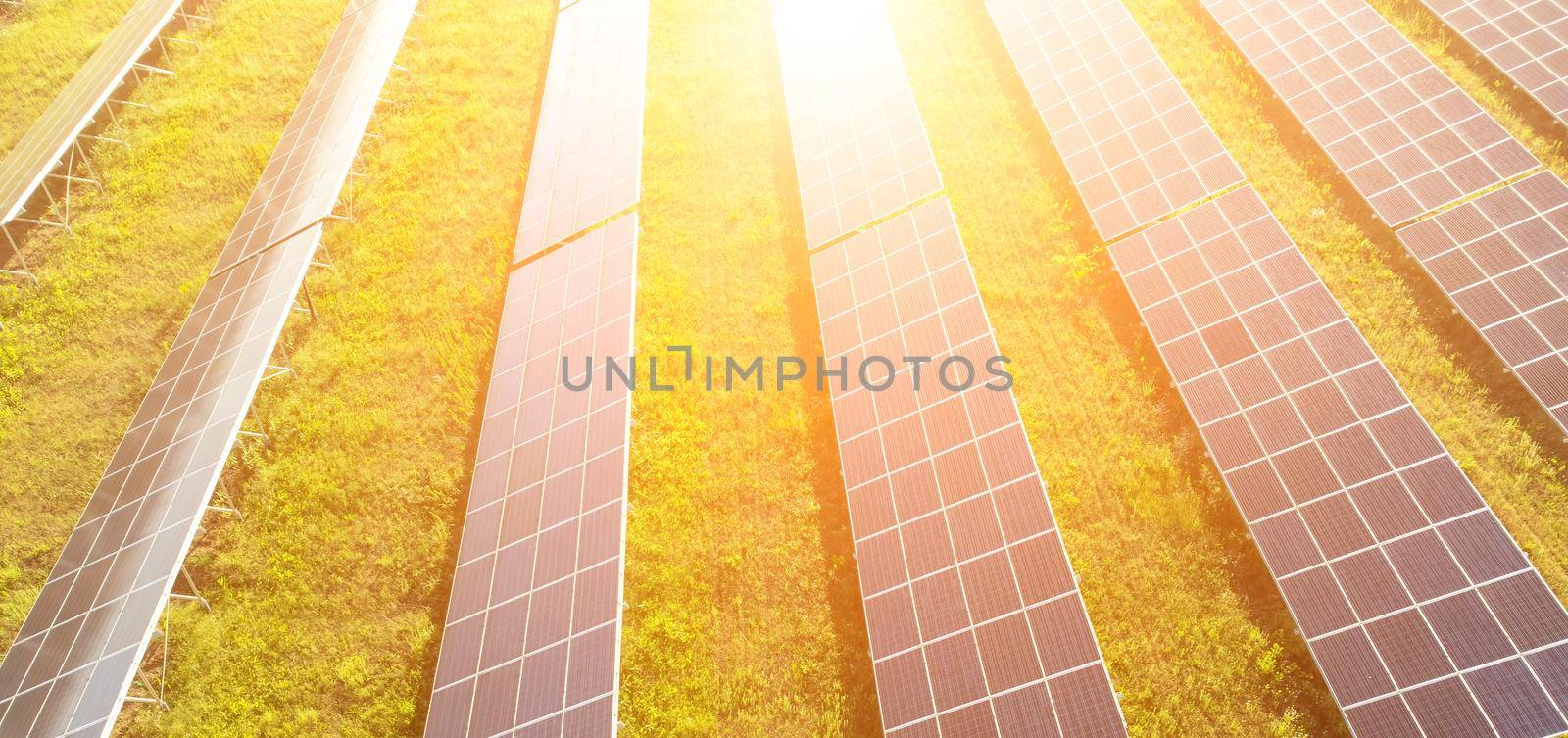 Aerial top view of a solar panels power plant. Photovoltaic solar panels at sunrise and sunset in countryside from above. Modern technology, climate care, earth saving, renewable energy concept