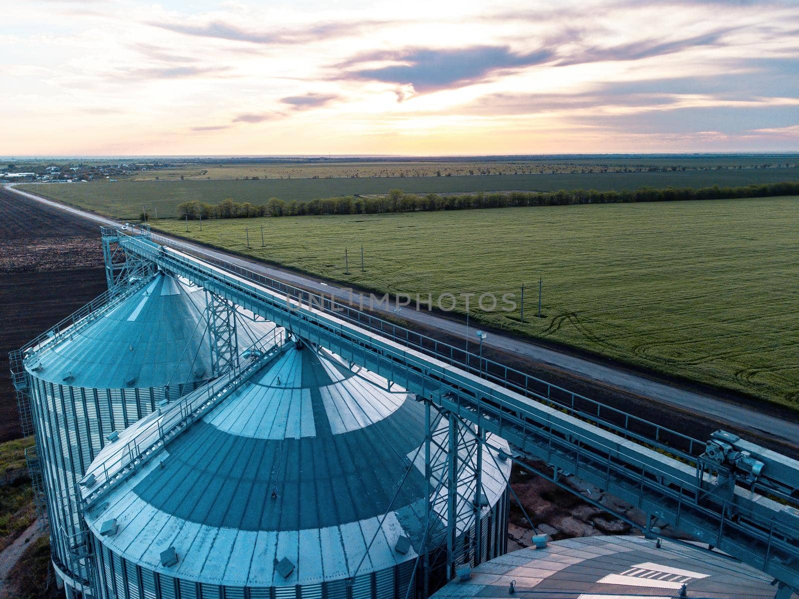 Grain elevator. Metal grain elevator in agricultural zone. Agriculture storage for harvest. Grain silos on green nature background. Exterior of agricultural factory