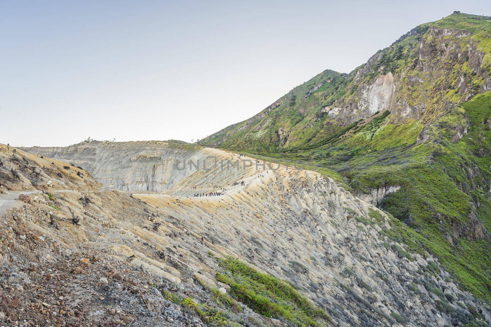 The magnificent views on green mountains from a mountain road trecking to the Ijen volcano or Kawah Ijen on the Indonesian language. Famous volcano containing the biggest in the world acid lake and sulfur mining spot at the place where volcanic gasses come from the volcano. Tourists hike this road to meet the sunrise at the volcano.