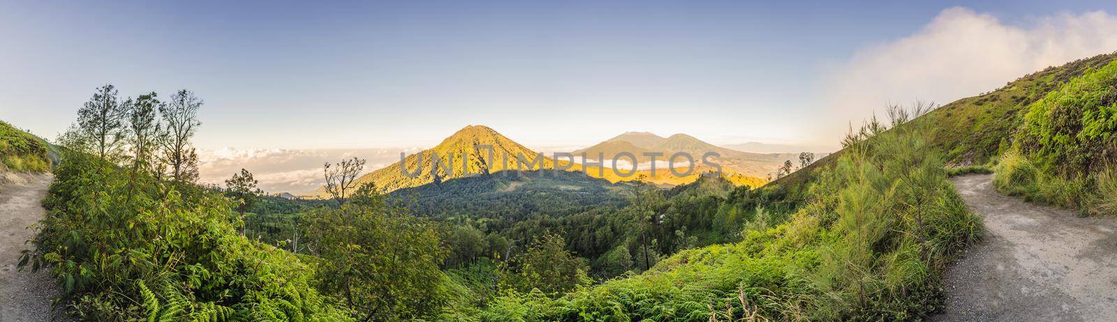 The magnificent views on green mountains from a mountain road trecking to the Ijen volcano or Kawah Ijen on the Indonesian language. Famous volcano containing the biggest in the world acid lake and sulfur mining spot at the place where volcanic gasses come from the volcano. Tourists hike this road to meet the sunrise at the volcano by galitskaya