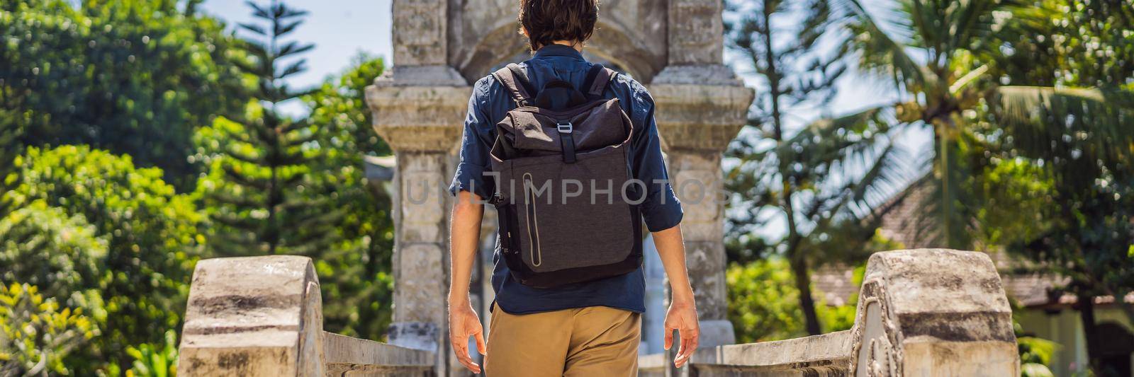 Young man in Water Palace Soekasada Taman Ujung Ruins on Bali Island in Indonesia. Amazing old architecture. Travel and holidays background BANNER, LONG FORMAT by galitskaya