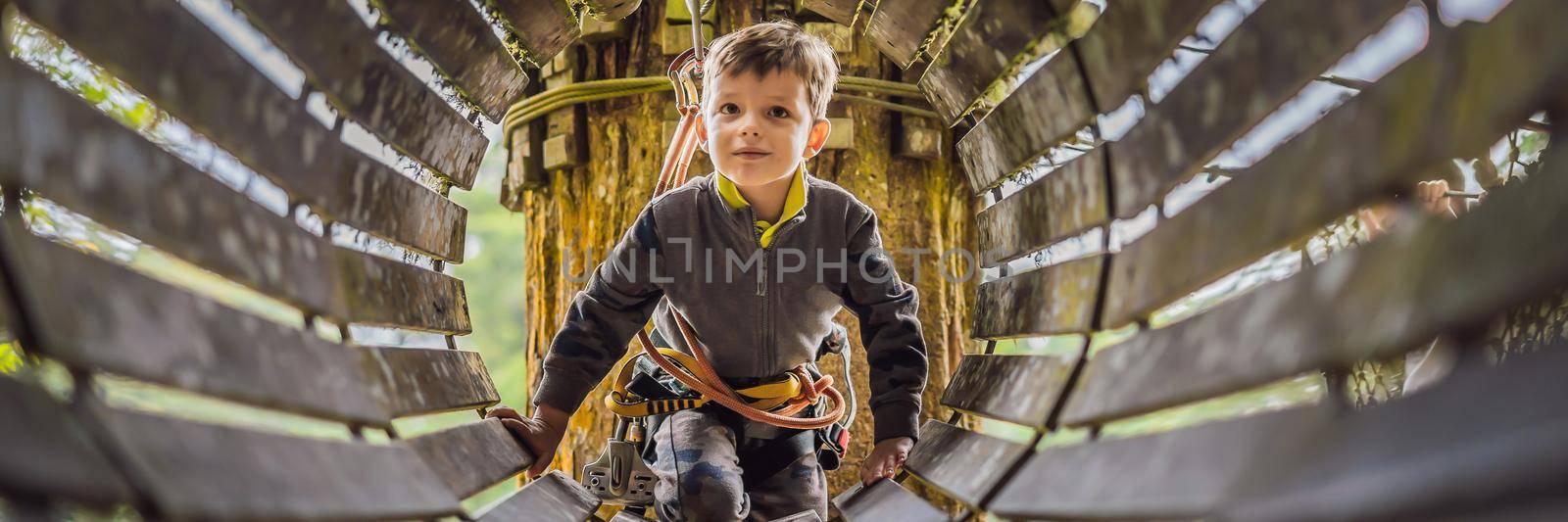 Little boy in a rope park. Active physical recreation of the child in the fresh air in the park. Training for children BANNER, LONG FORMAT by galitskaya