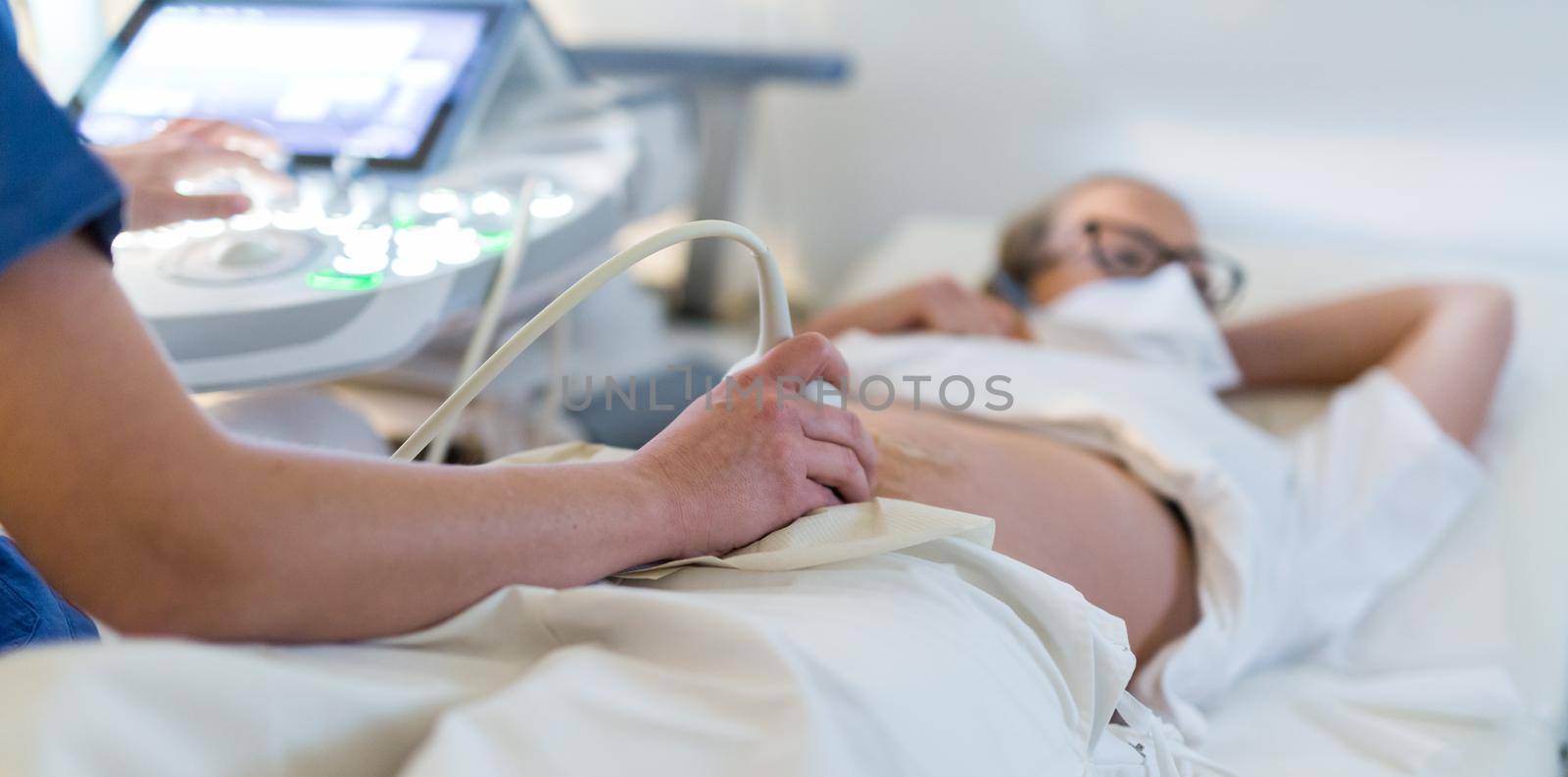 Close up of a pregnant woman having ultrasound scanning at the medical clinic. Healthcare and medicine concept by kasto
