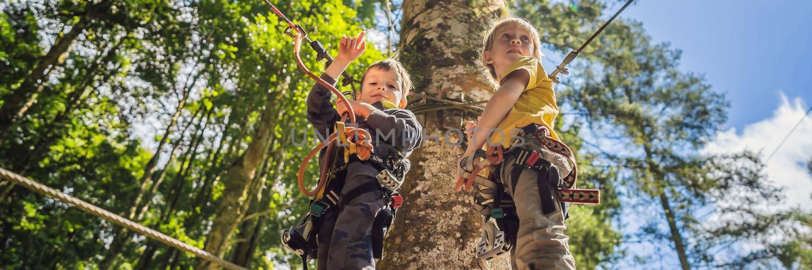 Two little boys in a rope park. Active physical recreation of the child in the fresh air in the park. Training for children. BANNER, LONG FORMAT