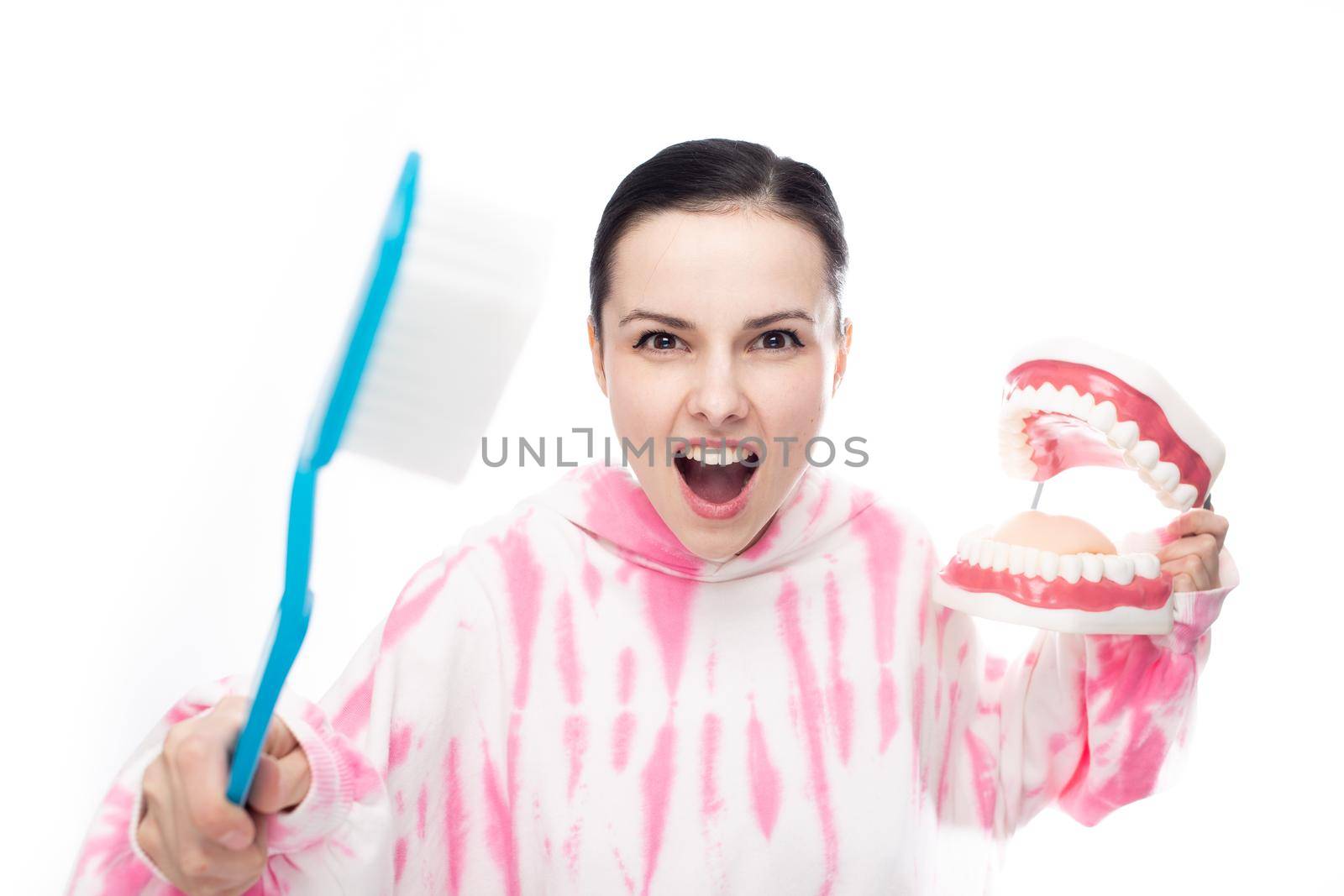 fighting brunette with a huge toothbrush and a tooth jaw in her hands, on a white background. High quality photo