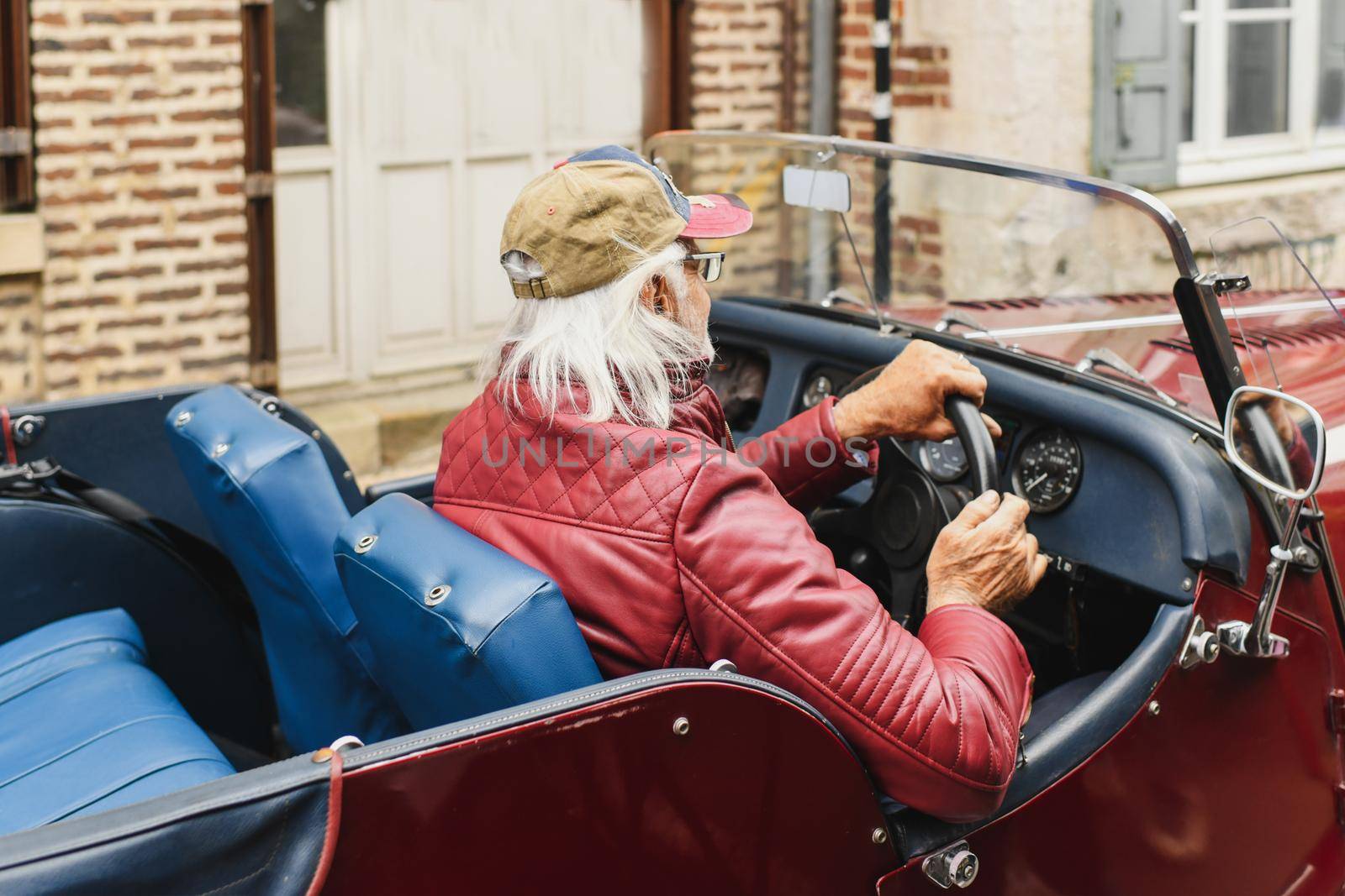 Grey-haired grandfather drives a vintage car