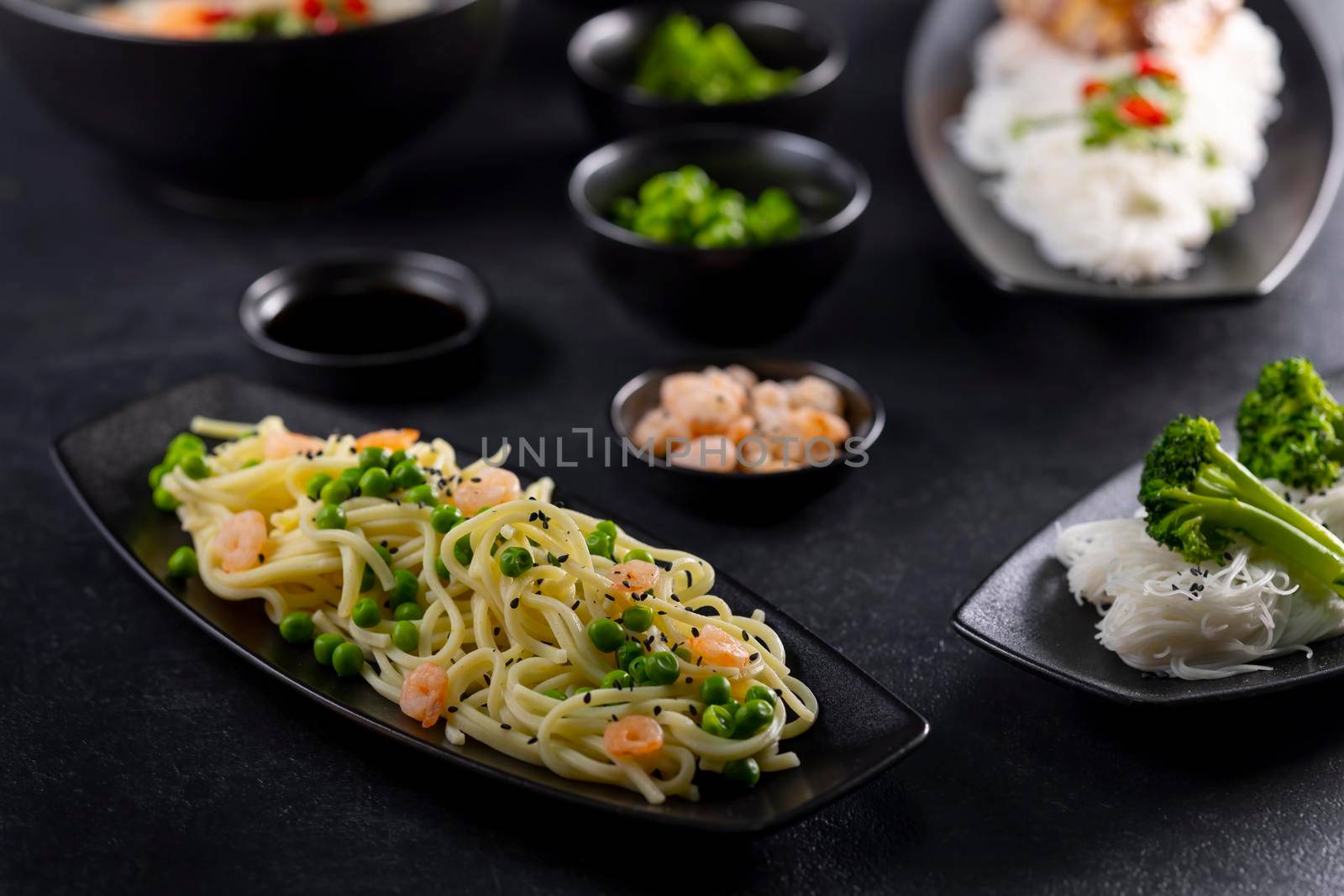 Various dishes of Asian cuisine with different types noodles and rice with shrimp, vegetables and black sesame