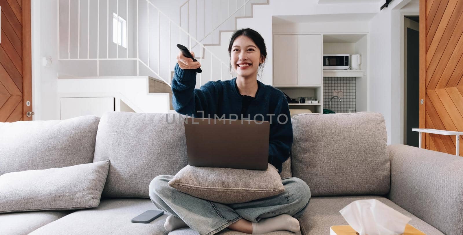 Asian young beautiful woman watching fun movie on television at home. Attractive casual girl feel happy and relax, sit on sofa having fun watch comedy video on TV in house. Activity lifestyles concept.
