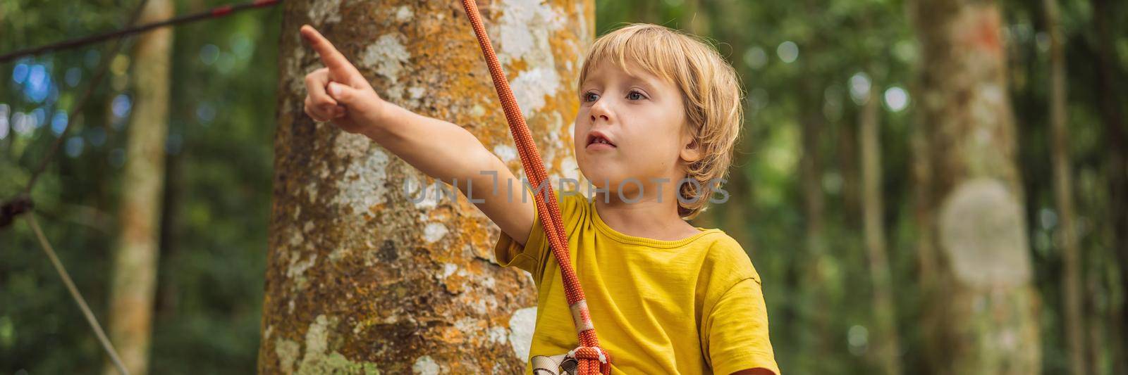 Little boy in a rope park. Active physical recreation of the child in the fresh air in the park. Training for children. BANNER, LONG FORMAT