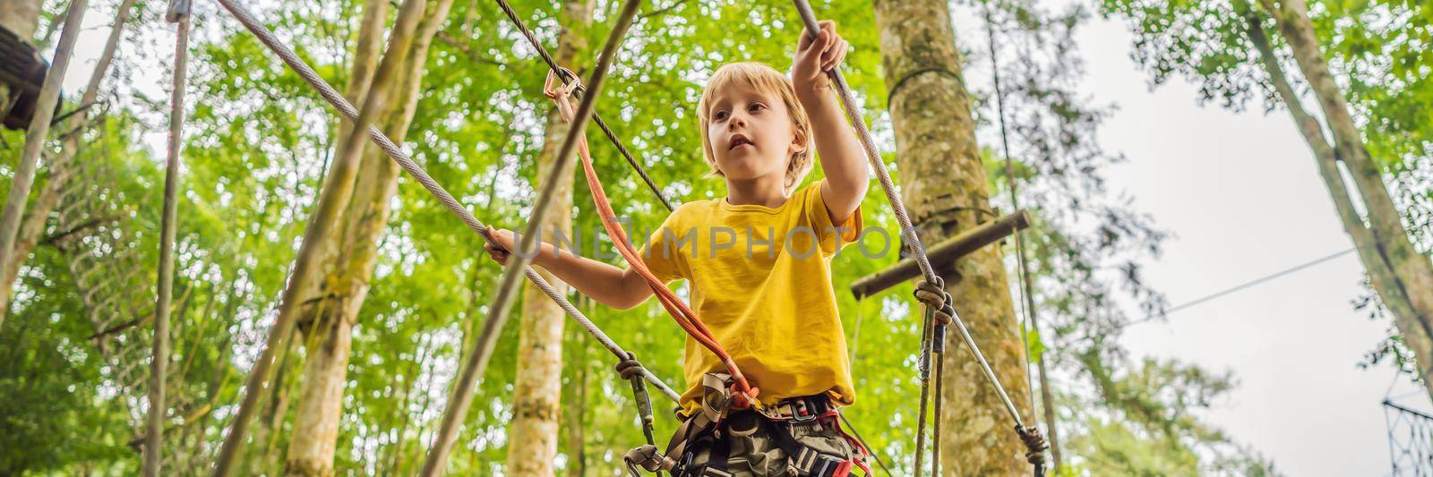 Little boy in a rope park. Active physical recreation of the child in the fresh air in the park. Training for children. BANNER, LONG FORMAT