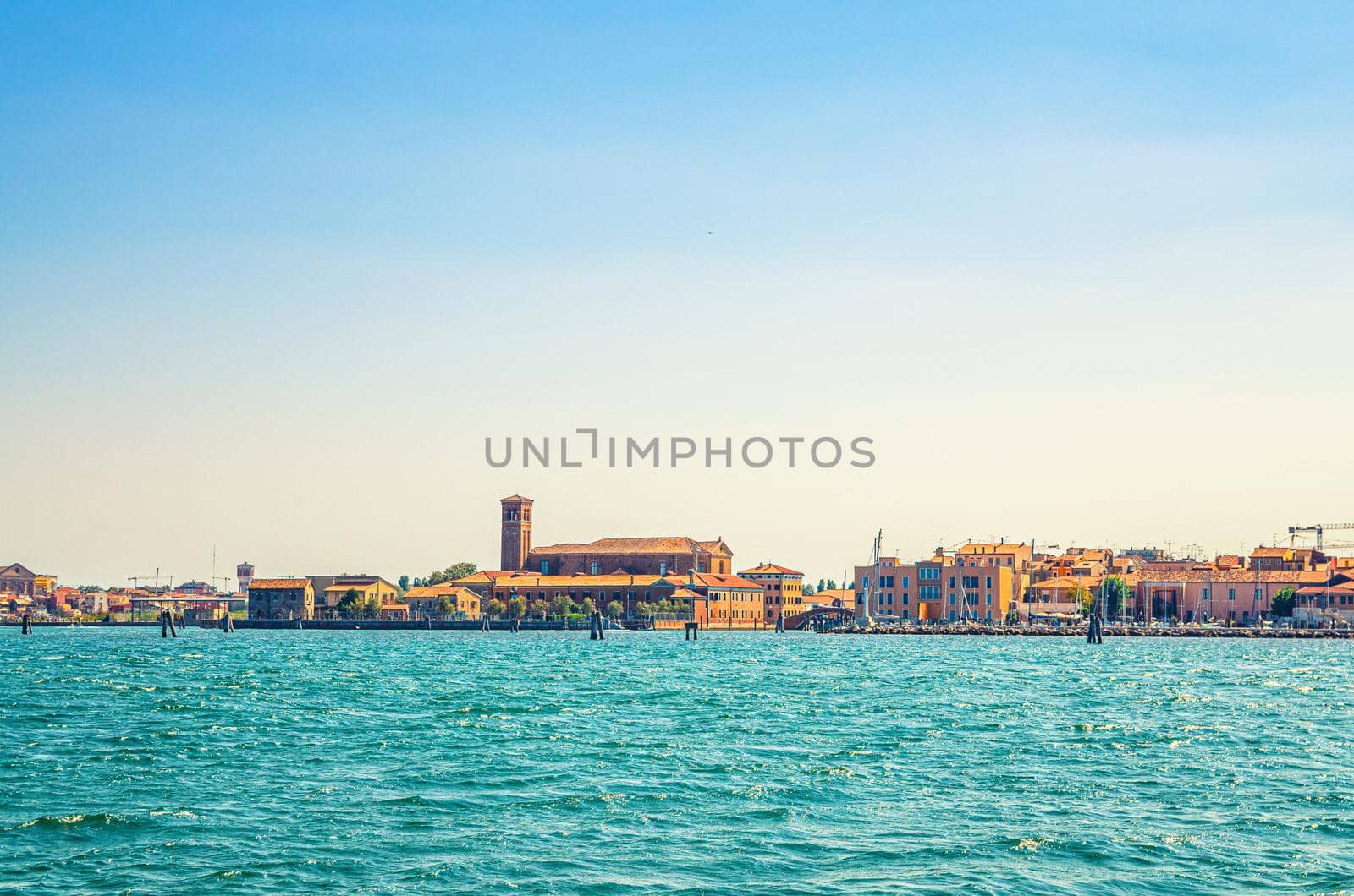 Panoramic view from sea lagoon of Chioggia town cityscape with Saint Domenico catholic church and old buildings in historical centre, blue sky background in summer day, Veneto Region, Northern Italy