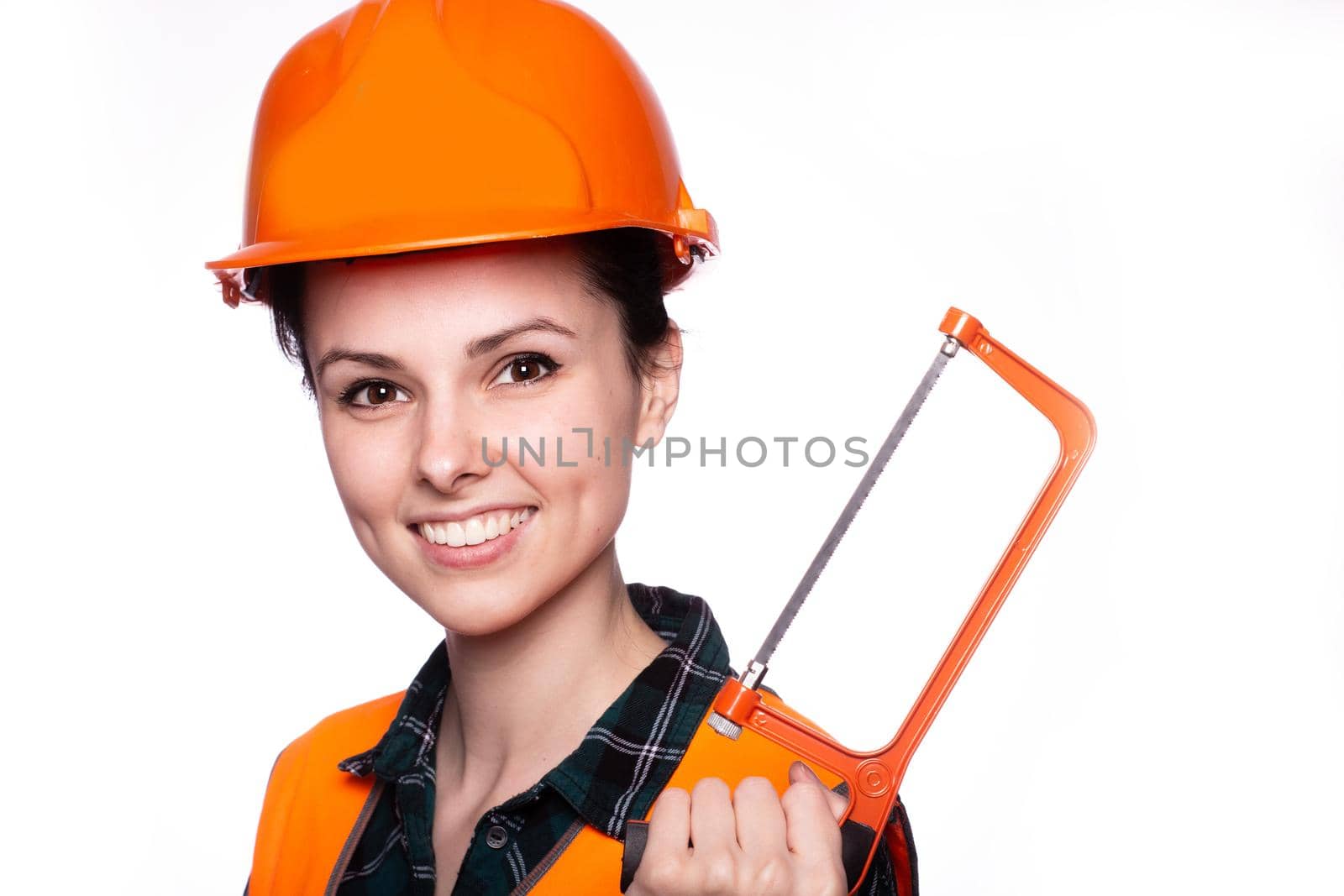 a woman in a construction helmet, and an orange vest holds a construction tool in her hand, white studio background, close-up portrait. High quality photo