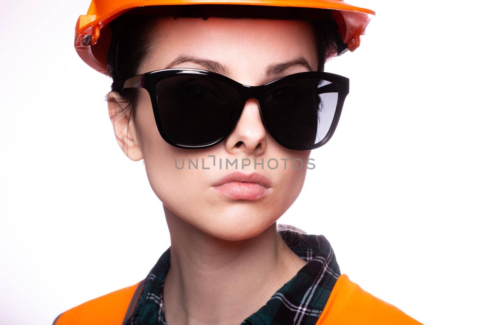woman in sunglasses construction safety helmet and orange vest, close-up portrait. High quality photo