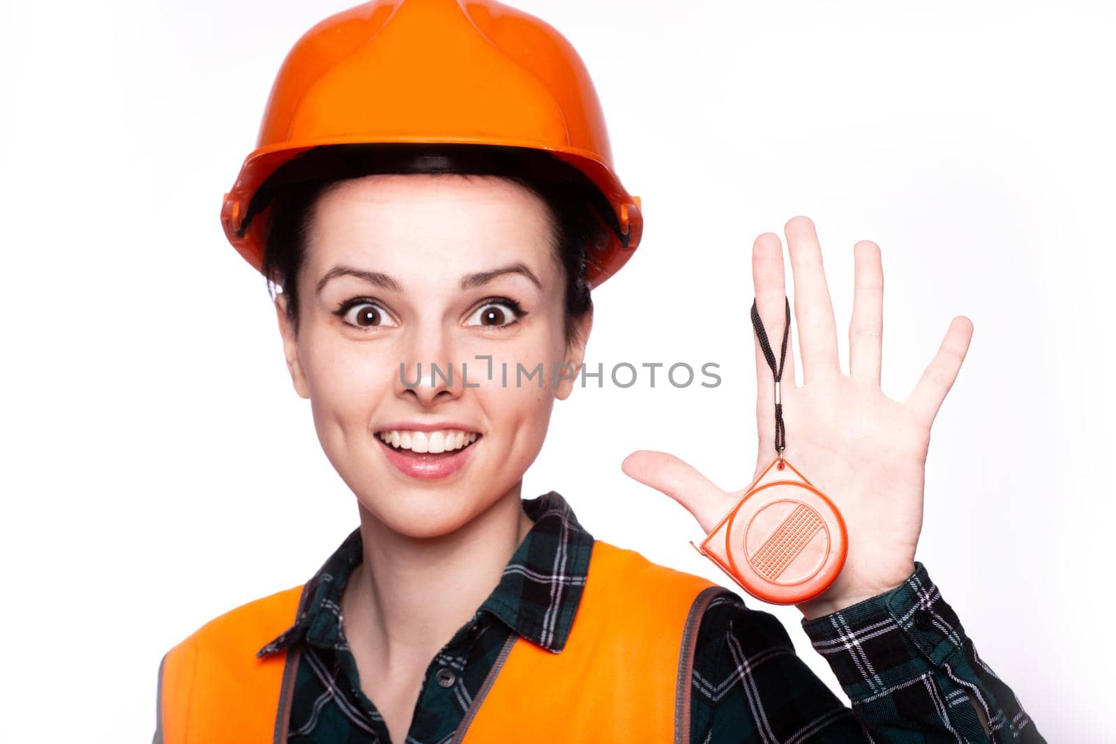 a woman in a construction helmet, and an orange vest holds a construction tool in her hand, white studio background, close-up portrait by shilovskaya