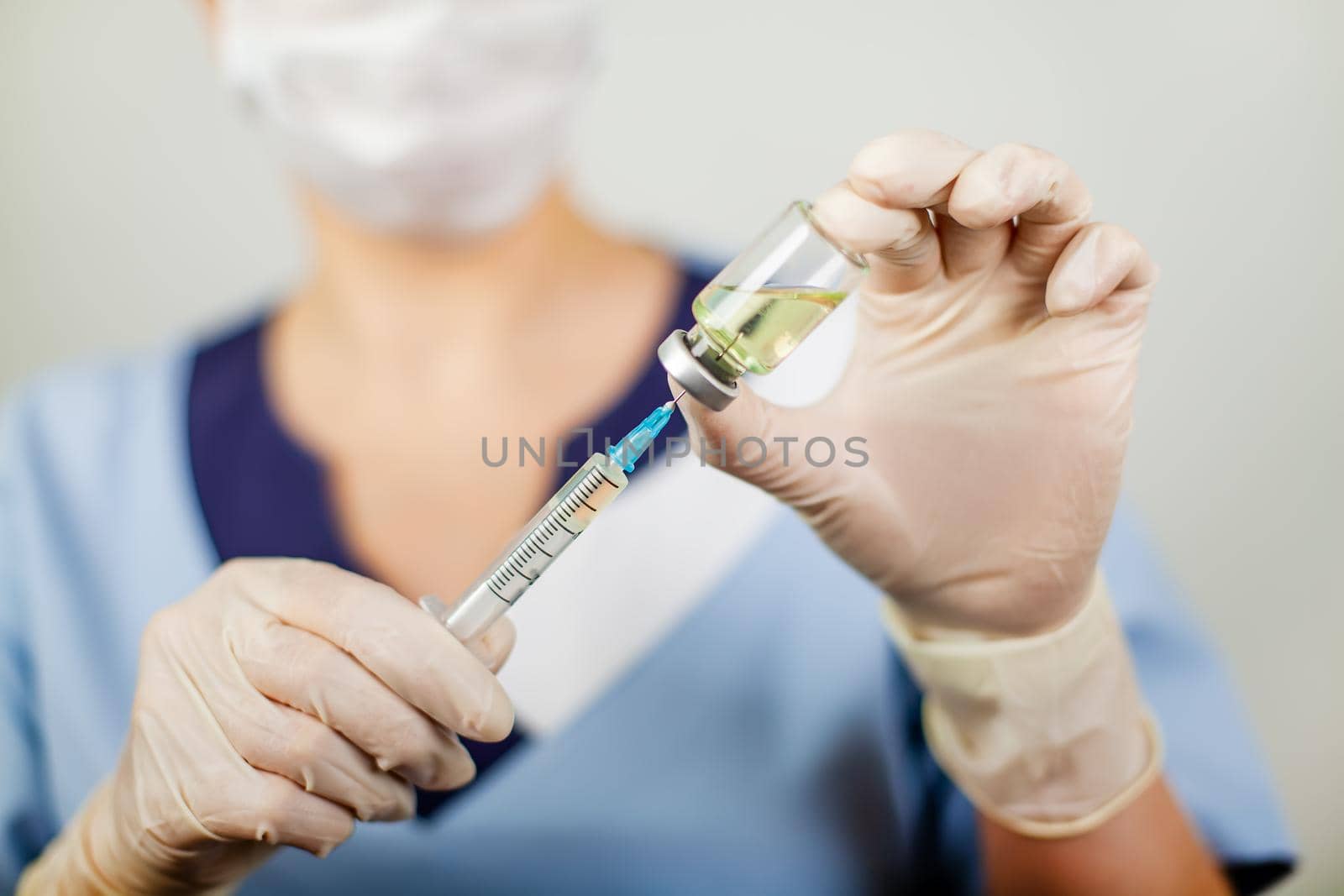 Hand of a doctor or nurse in nitrile gloves with a syringe needle vaccinated against influenza, measles, coronavirus COVID-19 for vaccinating children and adults, the concept of medicine and medicines