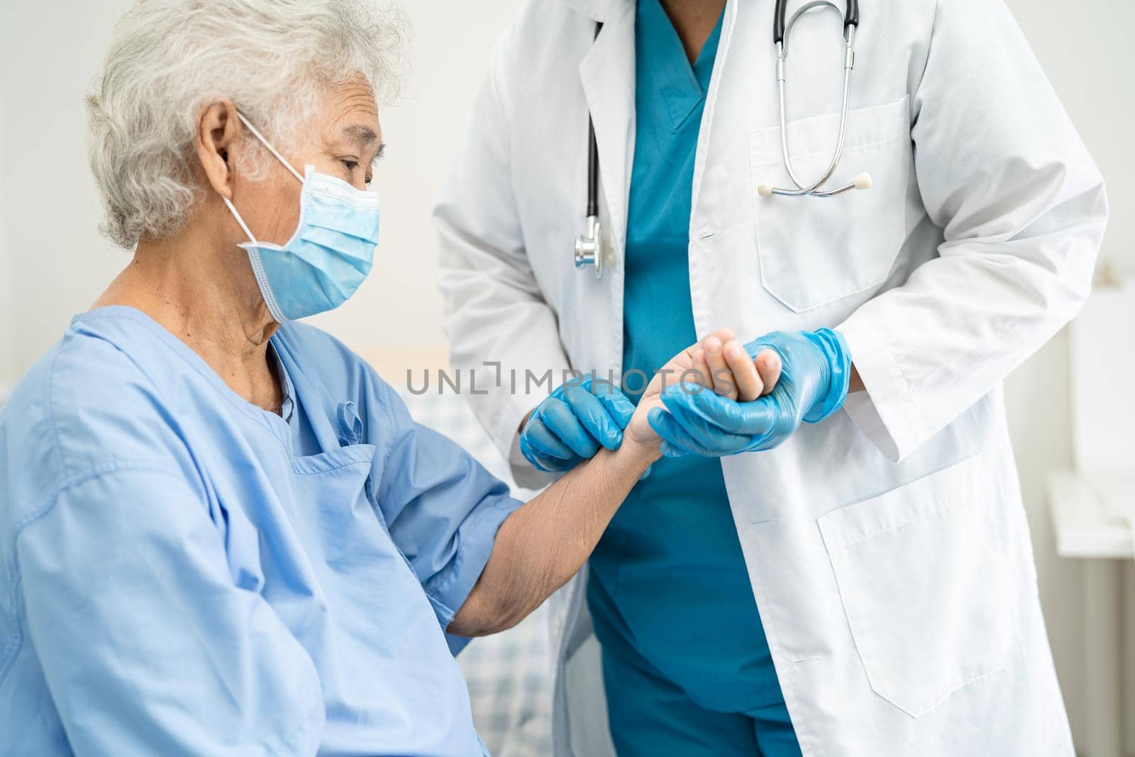 Doctor check Asian senior or elderly old lady woman patient wearing a face mask in hospital for protect safety infection Covid-19 Coronavirus.