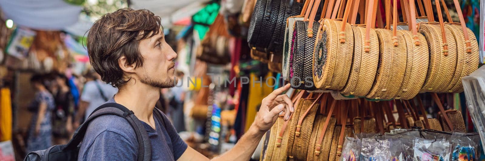 Man at a market in Ubud, Bali. Typical souvenir shop selling souvenirs and handicrafts of Bali at the famous Ubud Market, Indonesia. Balinese market. Souvenirs of wood and crafts of local residents BANNER, LONG FORMAT by galitskaya