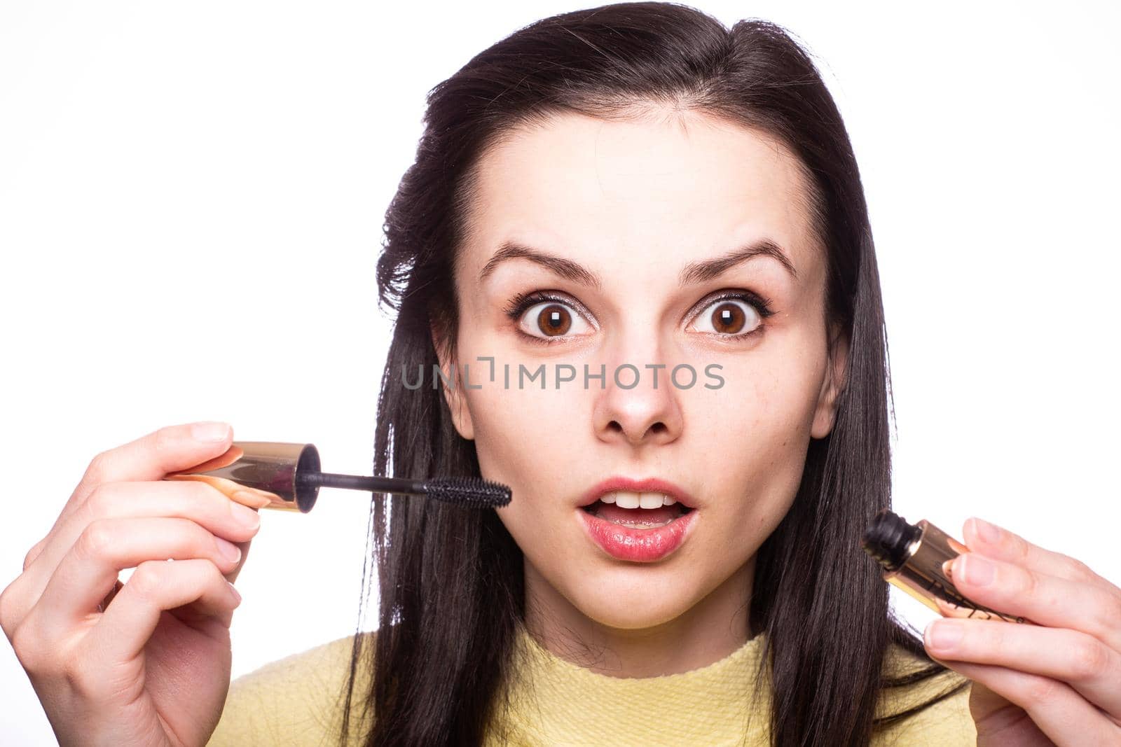 brunette woman in yellow sweater paints her lips with lipstick. High quality photo