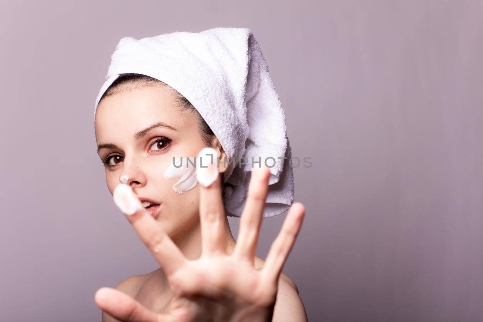 woman with white towel on her head and face cream. High quality photo