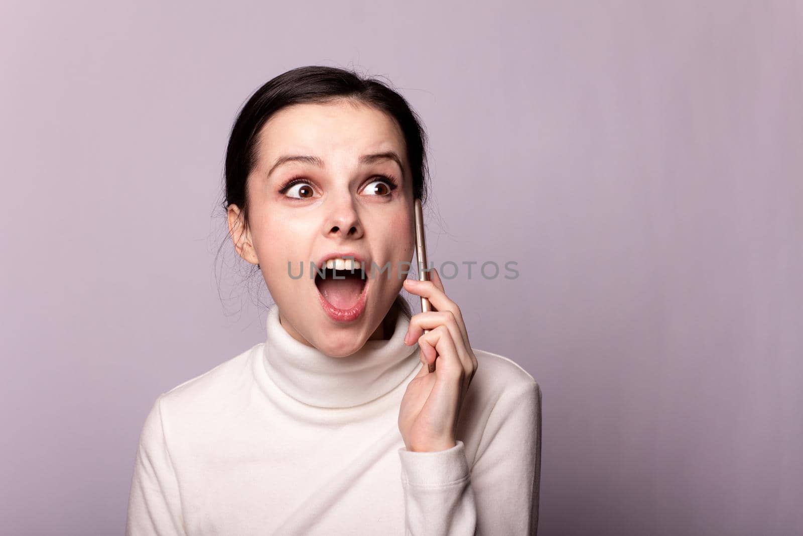 woman in a white turtleneck talking on the phone, portrait on a gray background by shilovskaya
