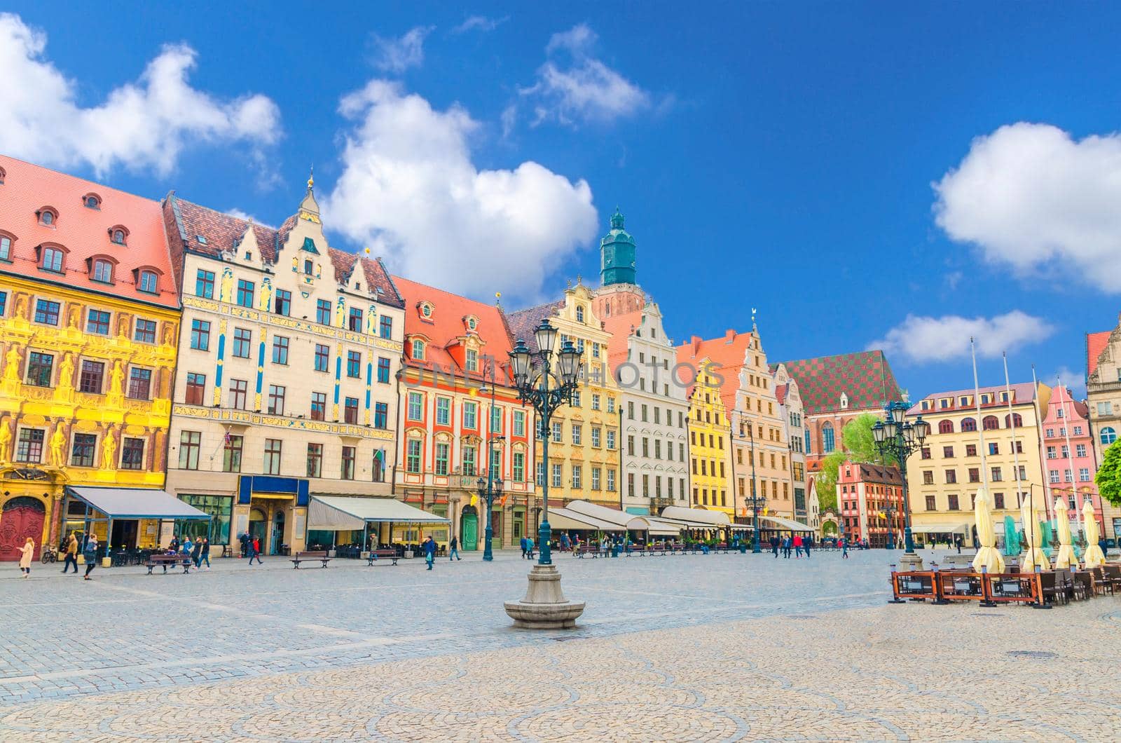 Row of colorful buildings with multicolored facade and St. Elizabeth Minor Basilica Garrison catholic Church on cobblestone Rynek Market Square in old town historical city centre of Wroclaw, Poland