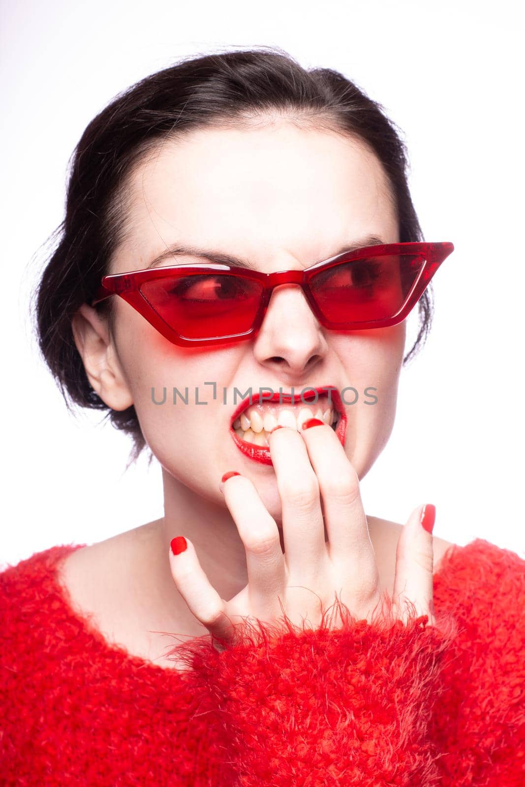 emotional brunette woman in red sunglasses, red nails, red lipstick, white background. High quality photo