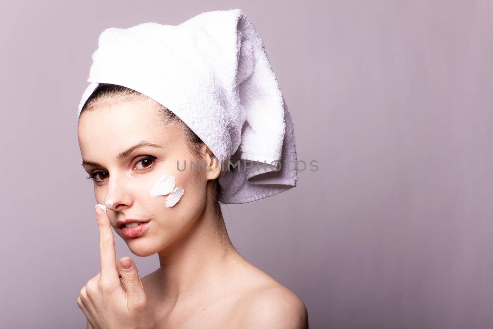 woman with white towel on her head and face cream. High quality photo