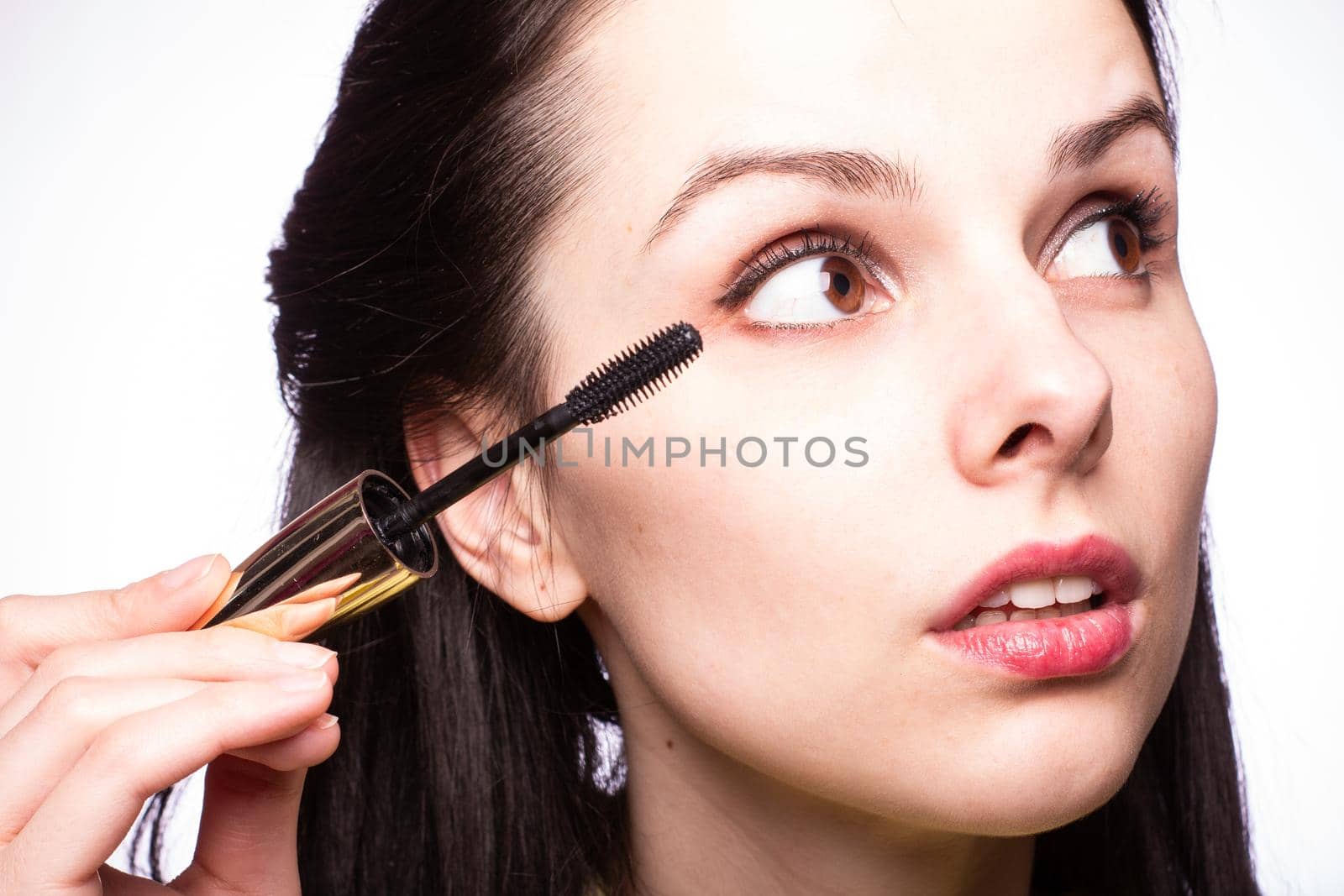 brunette woman in yellow sweater paints her lips with lipstick by shilovskaya