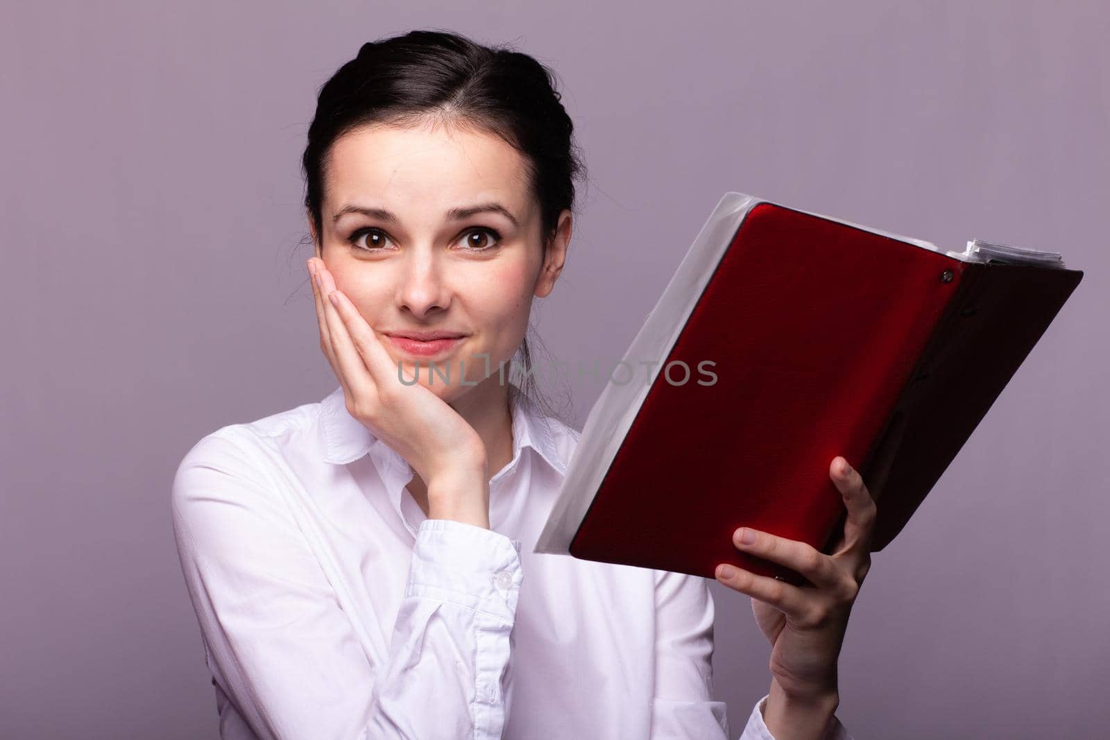 woman in a white shirt holds a red notebook in hand. High quality photo