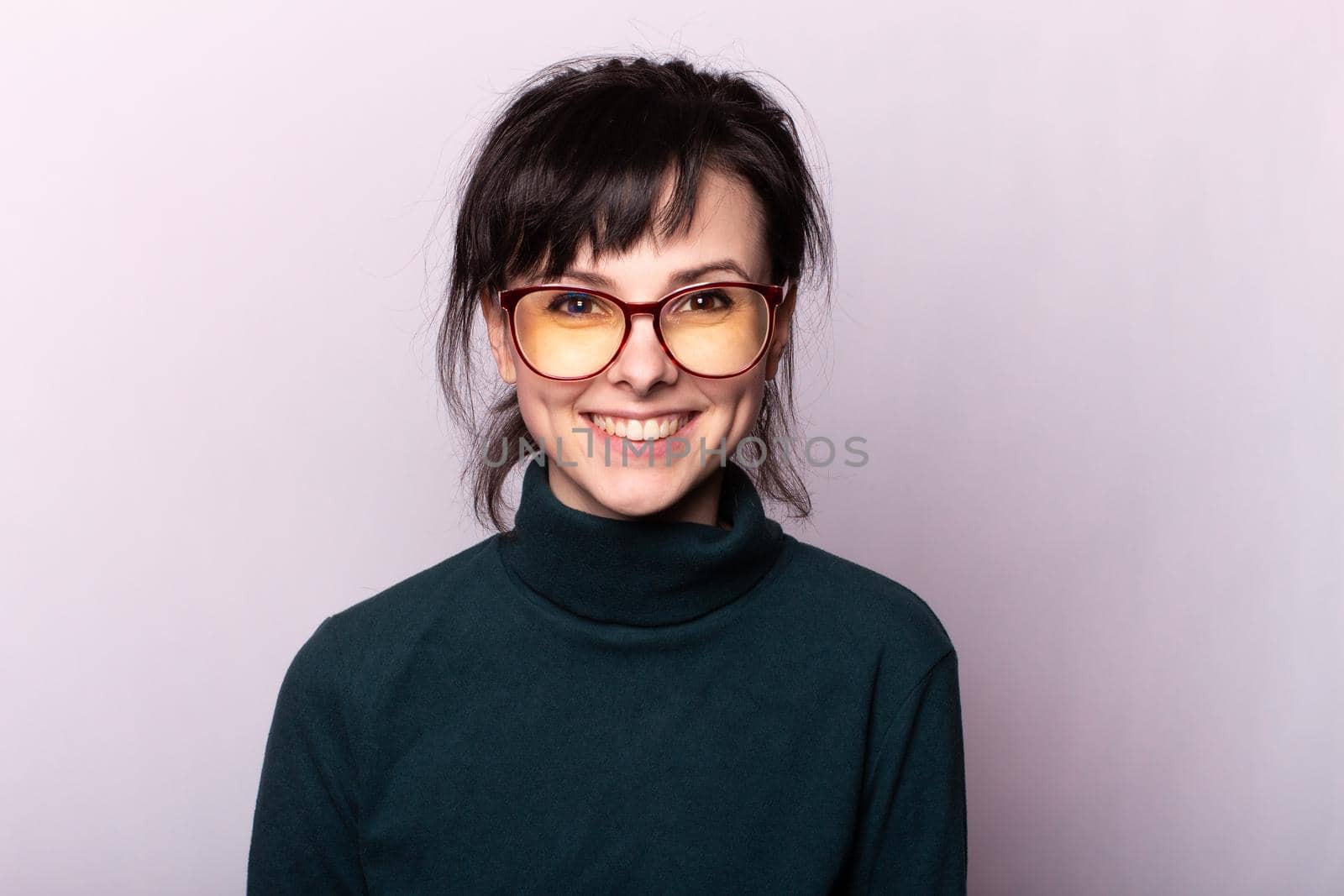 woman in a green turtleneck, glasses, portrait on a gray background. High quality photo