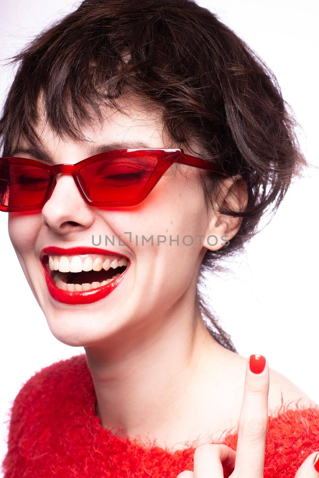 emotional brunette woman in red sunglasses, red nails, red lipstick, white background. High quality photo