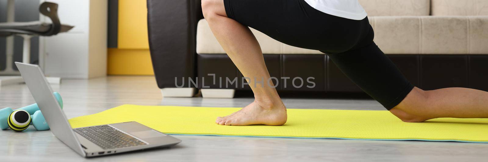 Woman doing stretching at home on a gymnastics mat, online workout. Relaxation after remote work, freelancer